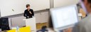 Bild: Frau an Pult im Hörsaal // Photo: Woman at a desk in a lecture hall