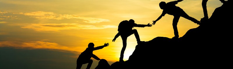 Photo: Three people climbing a mountain and helping each other