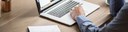 Photo: Detail of a person with a laptop at a desk